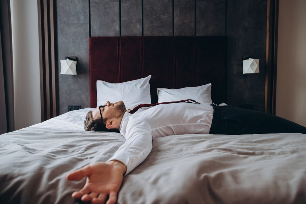 Exhausted businessman resting in bed due to jet lag Exhausted businessman resting in bed due to jet lag